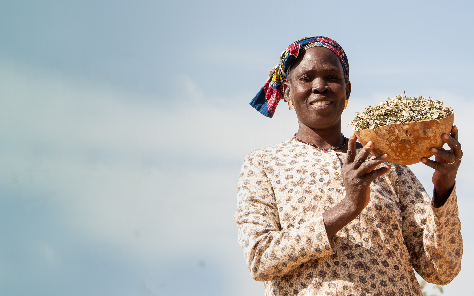 Mah, a woman on Tree Aid's She Grows project, holding up a bowl of leaves.