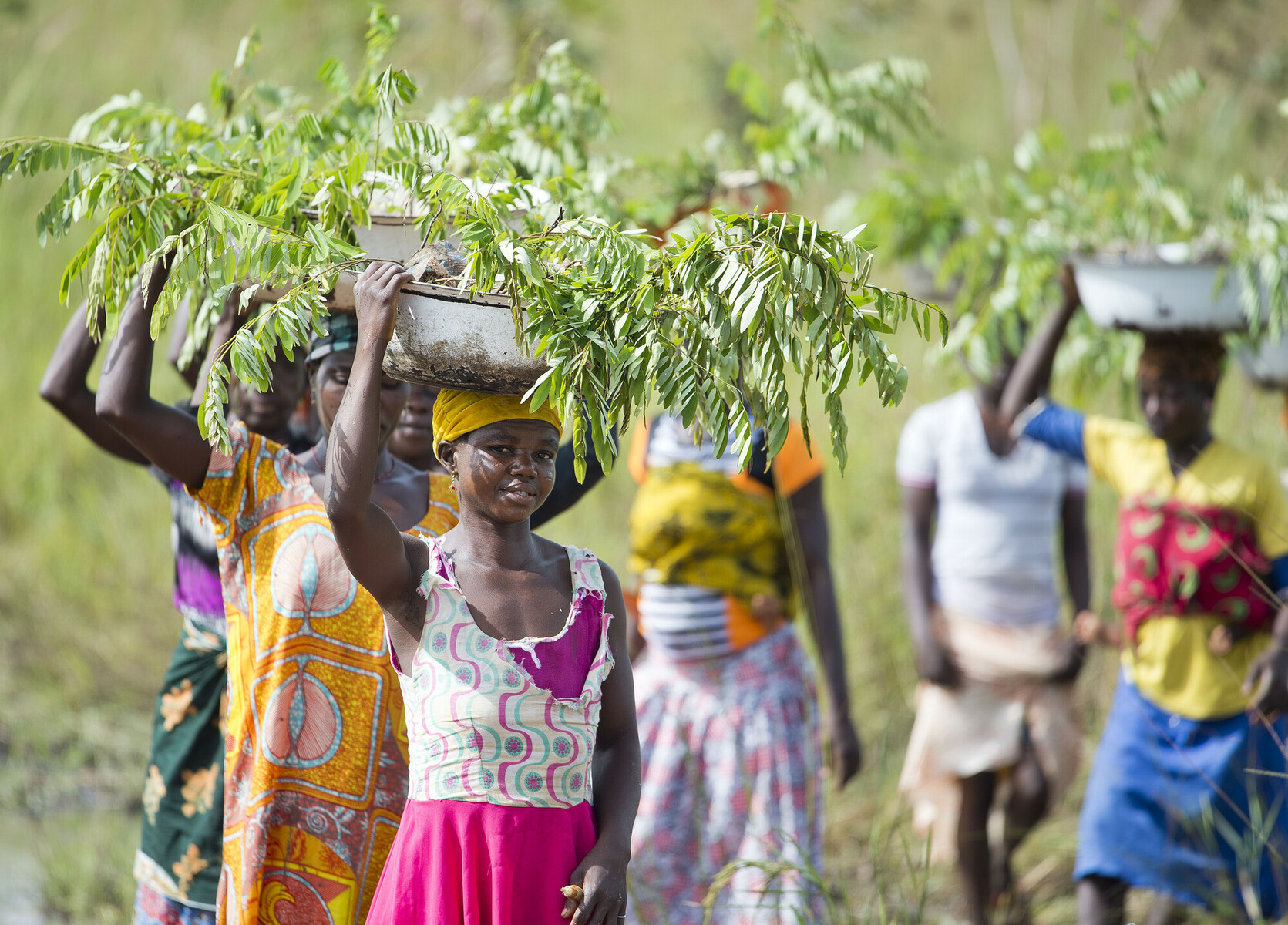 Jemila smiling and standing in front of a tree in her community 