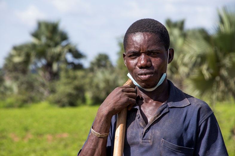 Soungalo, a farmer in Mali standing in a field looking and holding a hoe