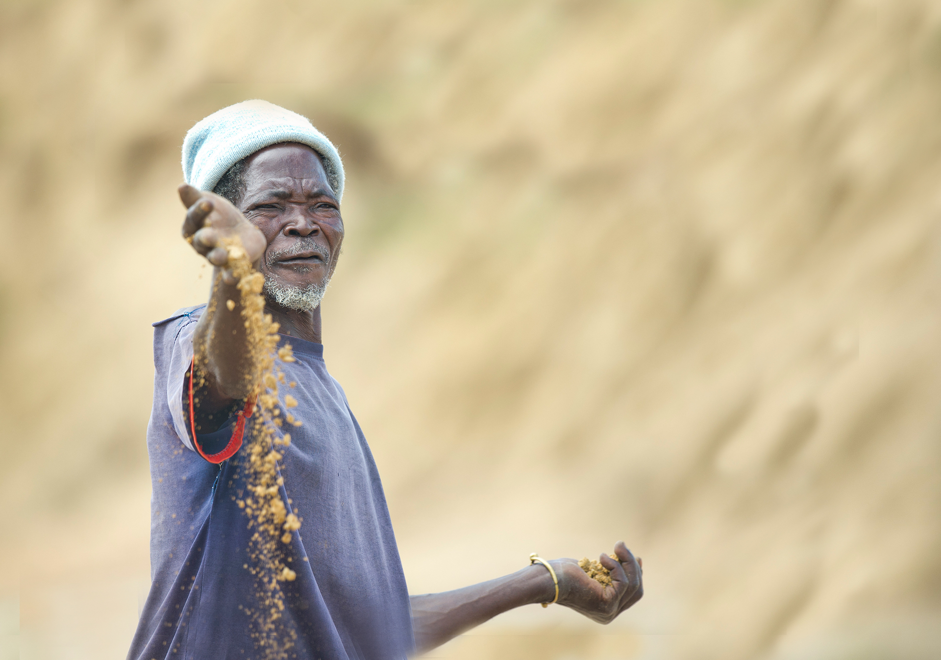 Mbole, a farmer in Ghana, holding up soil that has become so degraded that he can no longer farm on it. Photo credit, Rowan Griffiths, Daily Mirror.