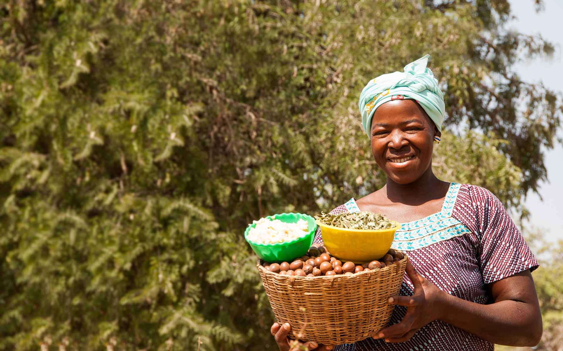Anè, a women taking part in a Tree Aid enterprise project in Mali, holding a basket of shea nuts.