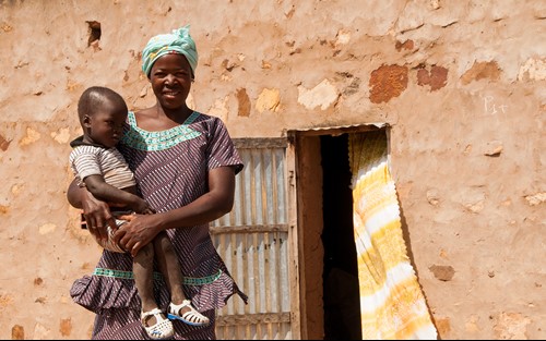 Image above: Ané who is part of the She Grows project, embracing her child outside her home