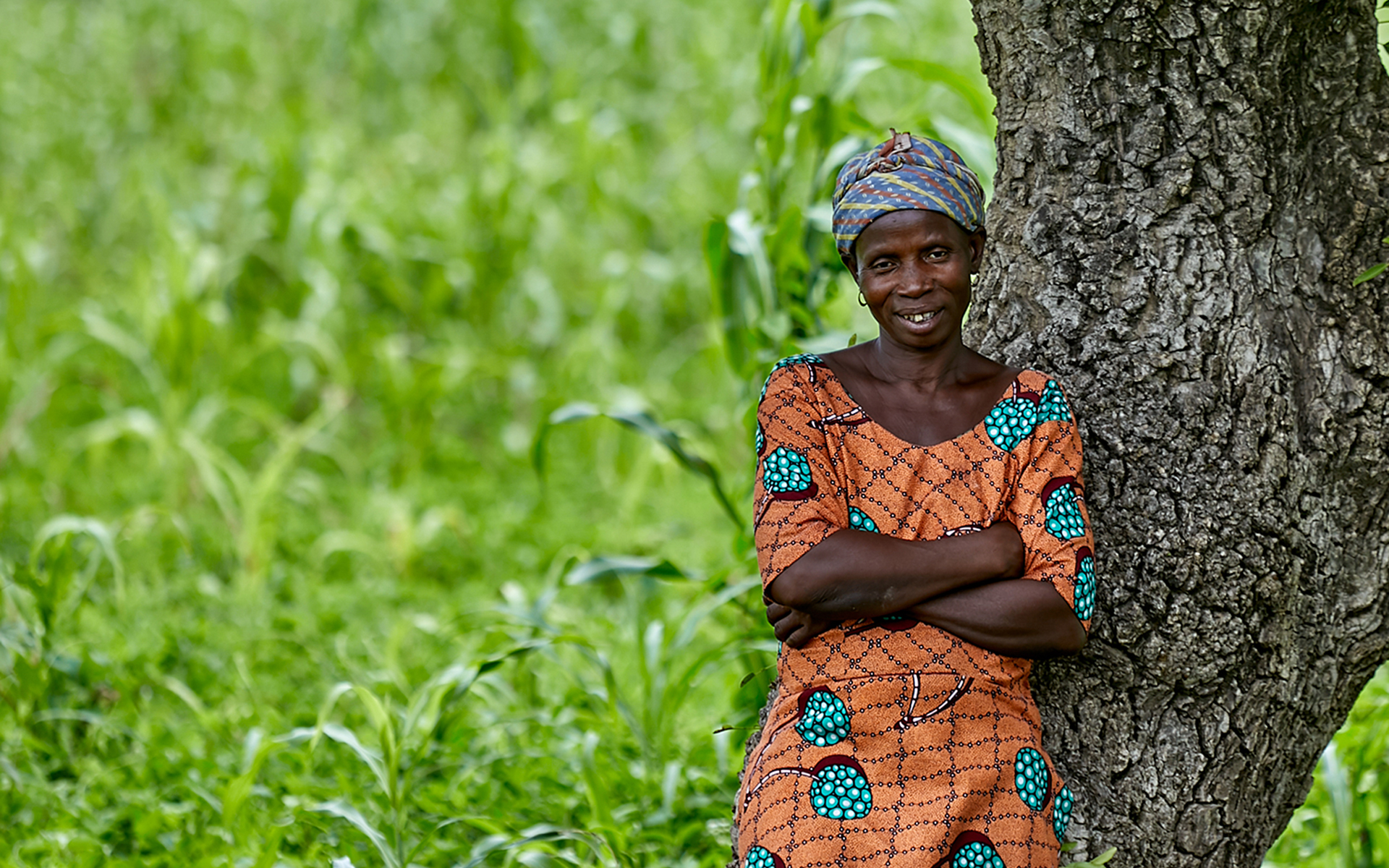Kubaje, a women that Tree Aid is working with in Ghana, leaning against a tree.