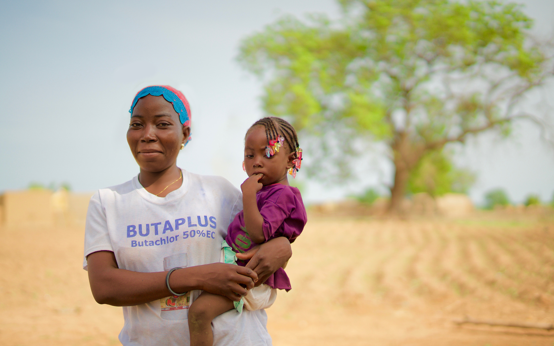 Zalissa, the secretary of her village's soumbala enterprise group, stood outside in arid land holding her baby