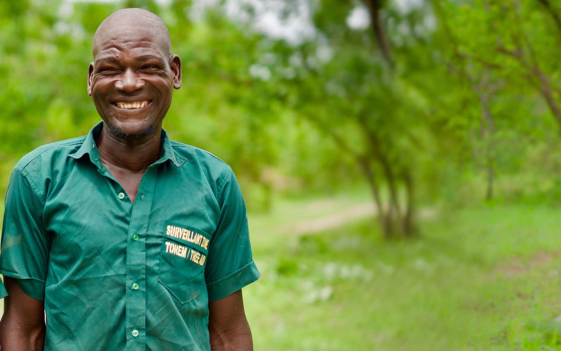 Mouni, a volunteer forest guard, smiling in front of his local forest.