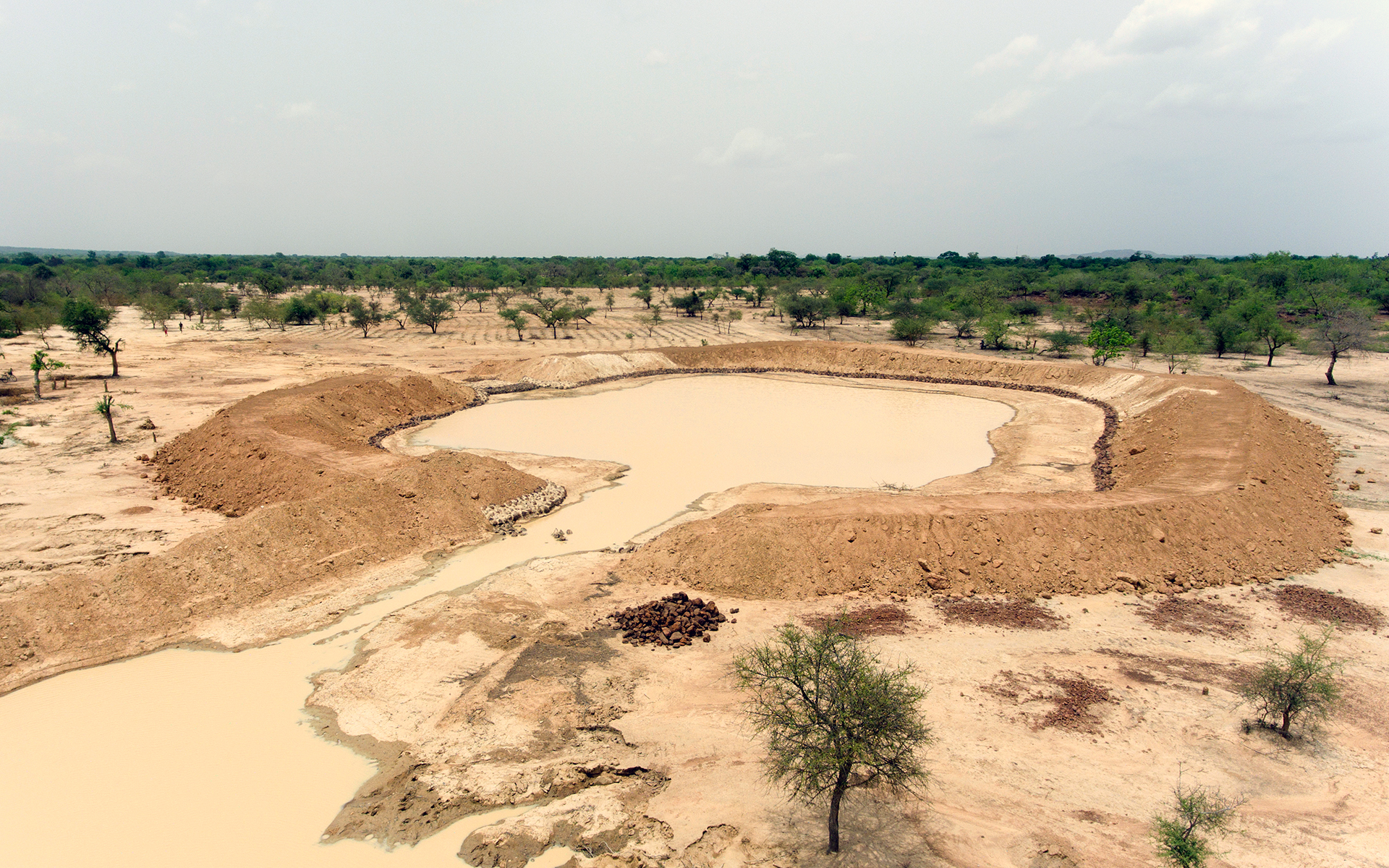 An aerial shot of a large pit of water in the land surrounded by trees - this is a bouli.